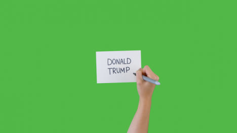 Mujer-Escribiendo-Donald-Trump-En-Papel-Con-Pantalla-Verde